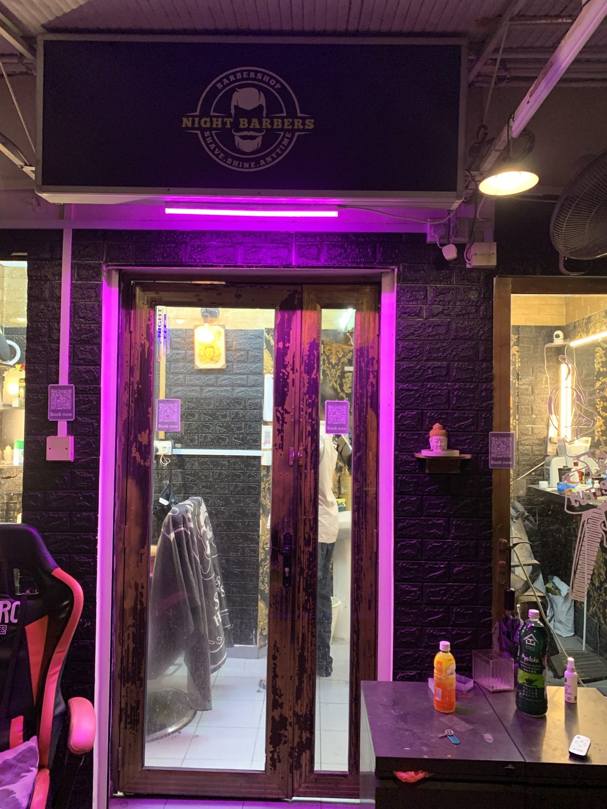 The neon-lit entrance to Night Barbers at night