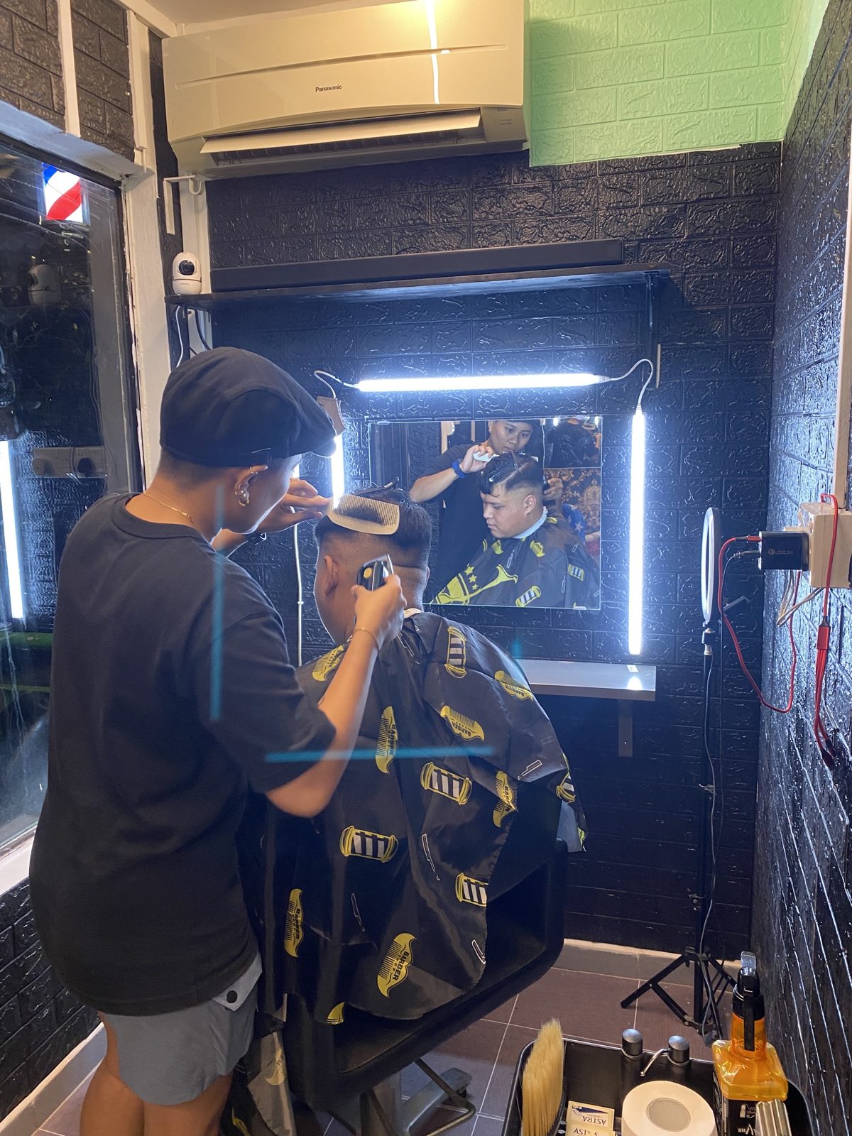 A barber working on a caped client